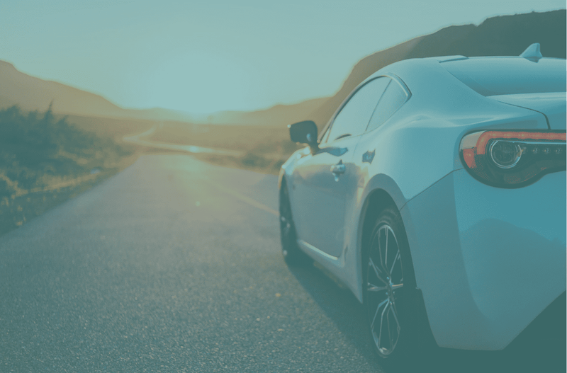 高級車が山道を走行する夕暮れの風景