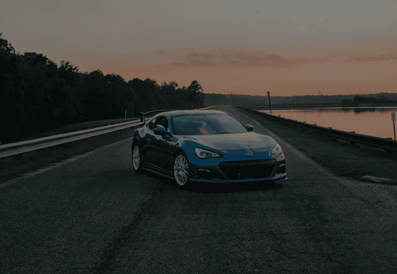 高級車が山道を走行する夕暮れの風景